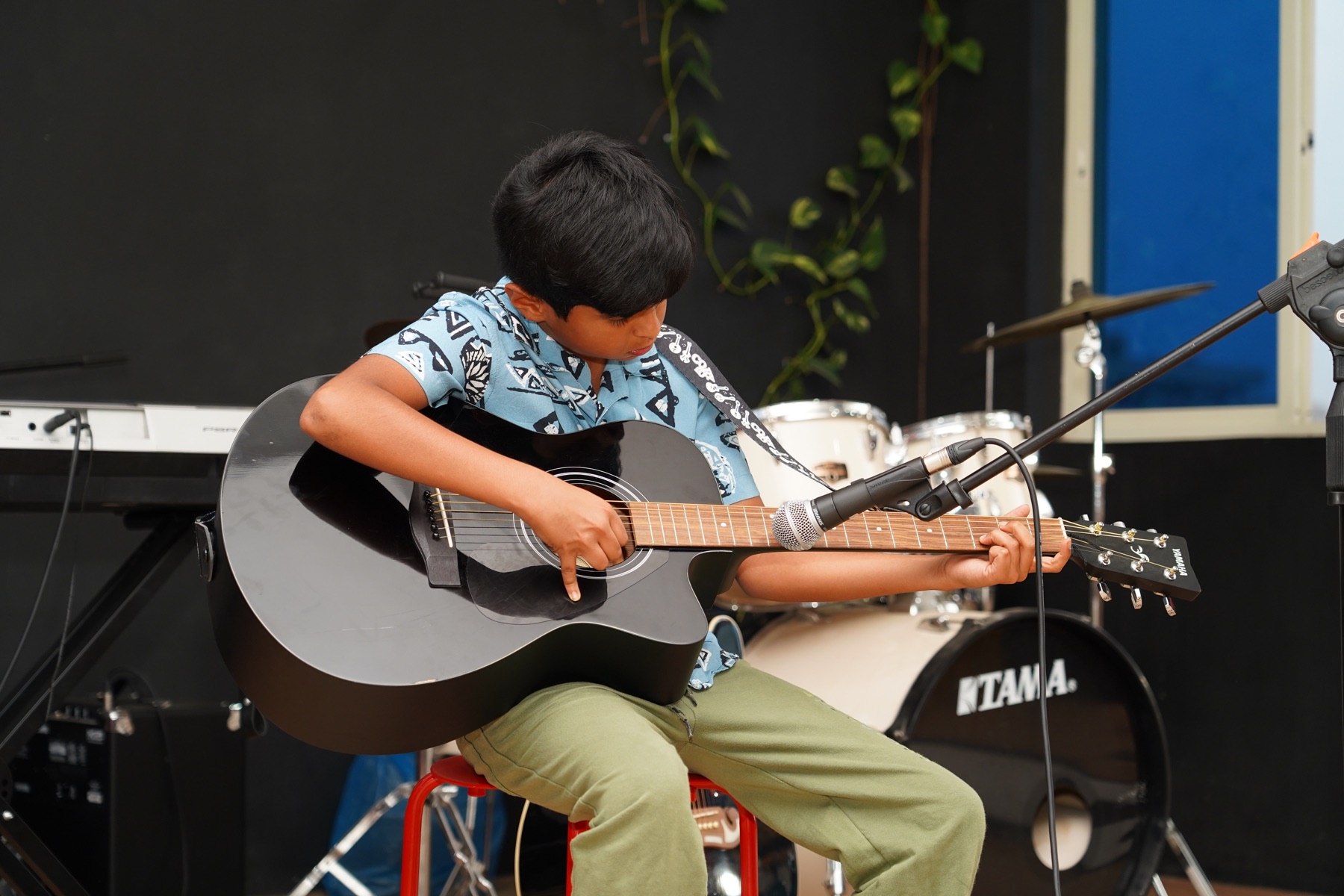 Young acoustic guitarist performing at a SARA Music School event