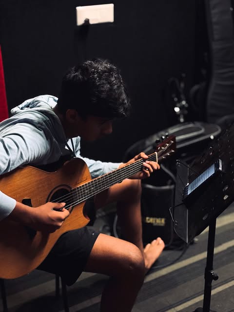 A SARA guitarist playing an acoustic guitar with sheet music