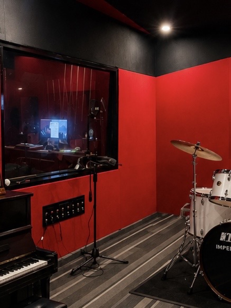 Drum kit, piano and recording booth inside SARA Music Studio